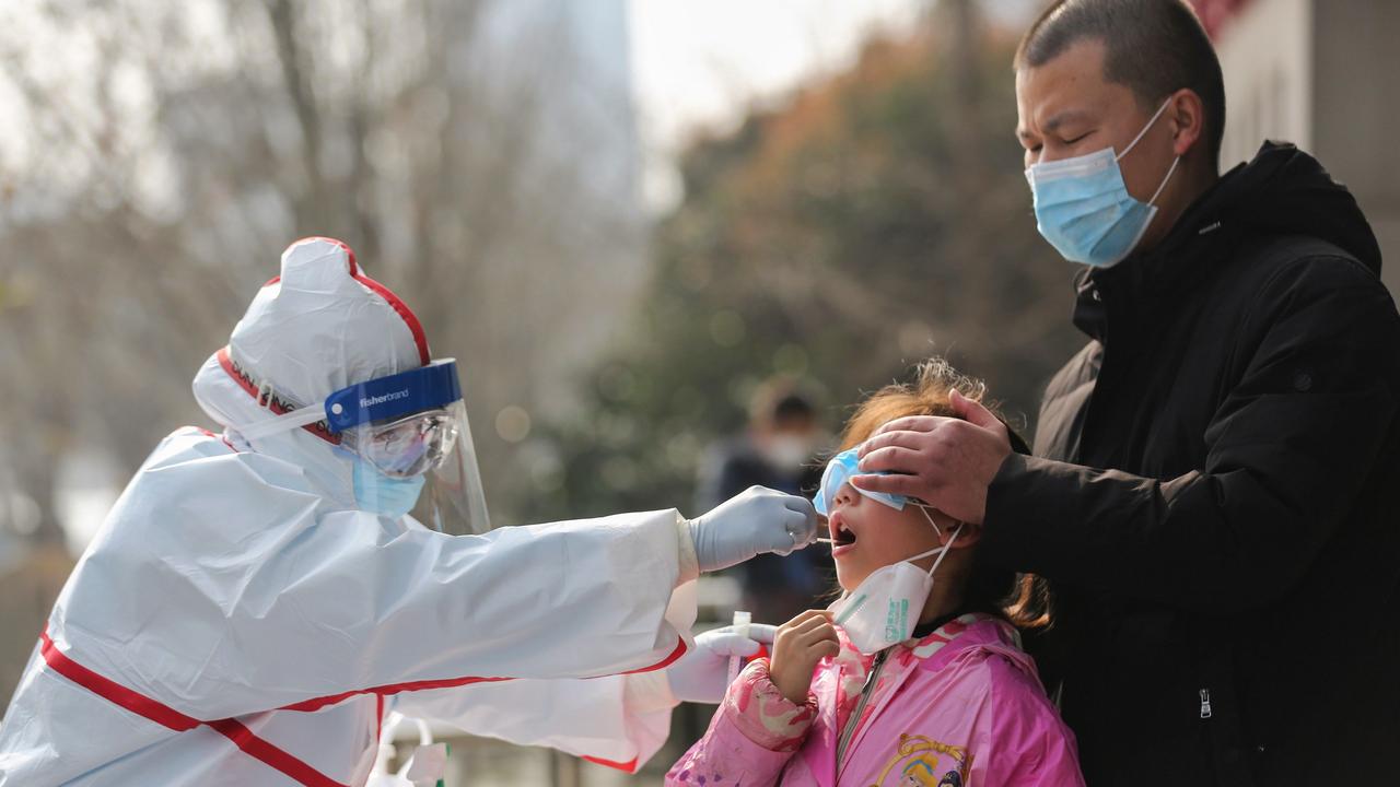 A medical staff member collects a sample from a girl for a coronavirus test in Wuhan. Picture: STR / AFP / China OUT