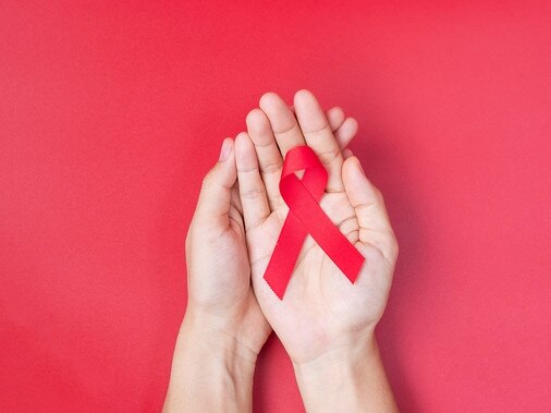 Hand holding Red Ribbon for supporting people living and illness. Healthcare and safe sex concept. December World Aids Day and multiple myeloma Cancer Awareness month