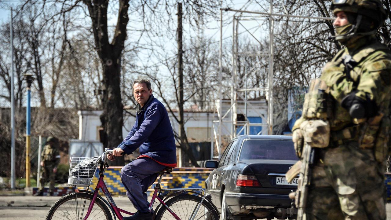 A man rides a bicycle by a Russian soldier standing guard in Volnovakhaa in the self-proclaimed Donetsk People's Republic (DNR). Picture: Alexander NEMENOV / AFP