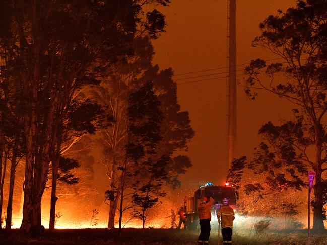 Firefighters hose down trees as they battle against bushfires around the town of Nowra in the Australian state of New South Wales on December 31, 2019. - Thousands of holidaymakers and locals were forced to flee to beaches in fire-ravaged southeast Australia on December 31, as blazes ripped through popular tourist areas leaving no escape by land. Picture: Saeed Khan/AFP