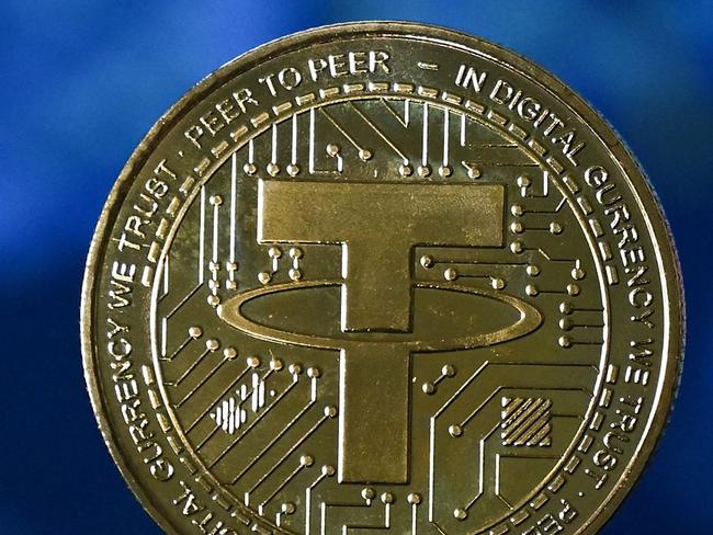 An illustration picture taken in London on May 8, 2022, shows a gold plated souvenir cryptocurrency Tether (USDT) coin arranged beside a screen displaying a trading chart. - Tether (USDT) is an Ethereum token known as a stablecoin that is pegged to the value of the US dollar, and is currently the largest stablecoin with a market value of USD 83 billion dollars. (Photo by Justin TALLIS / AFP)