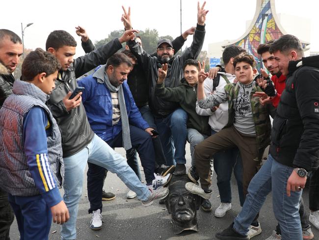 Syrians pose with a vandalized statue of Hafez al-Assad, father of Bashar al-Assad, in Umayyad Square on December 8, 2024 in Damascus, Syria. Picture: Ali Haj Suleiman/Getty Images