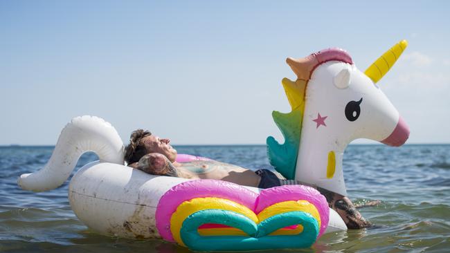 German tourist Marcel Trezenschik cools off in Elwood beach on an inflatable unicorn. Picture: Eugene Hyland