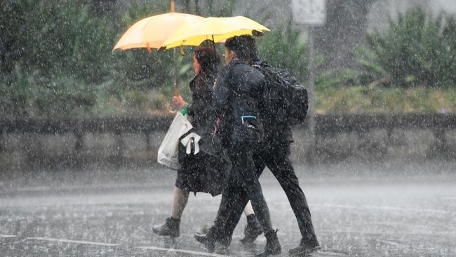 Pedestrians hold umbrellas as they walk in heavy rain in Sydney's CBD on Friday.