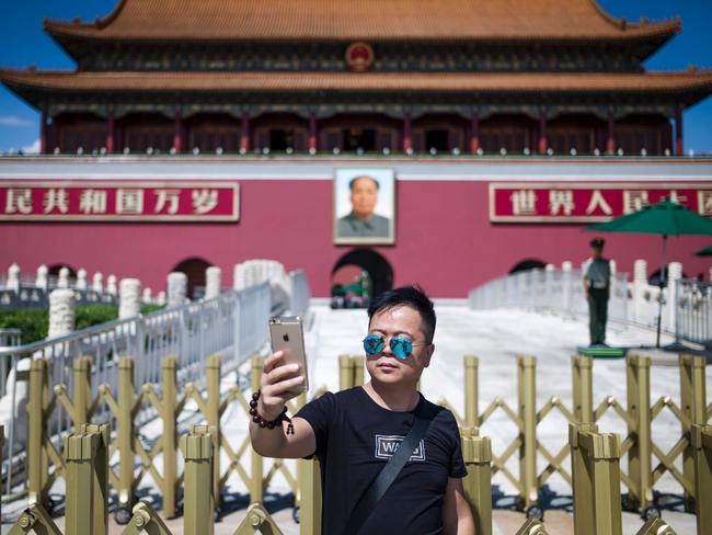 A tourist takes a selfie in front of a giant portrait of Mao Zedong at the gate of the Forbidden City in Beijing on September 6. Picture: Fred Dufour/AFP