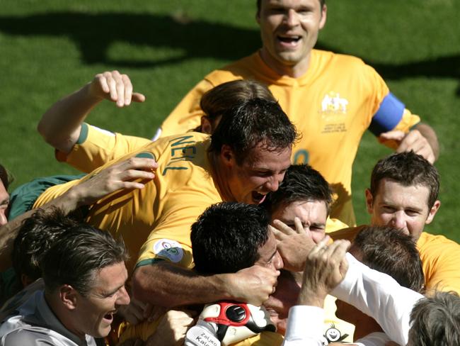 12/06/2006. Australian Socceroos coach Guus Hiddink, (bottom white shirt), celebrates with his players after John Aloisi scored his side's third goal during their World Cup Group F soccer match against Japan in Kaiserslautern, Germany. (AP Photo/Emilio Morenatti) ** MOBILE/ PDA USAGE OUT **