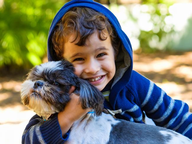 Cute boy enjoying the outdoors in a home yard setting with his dog.