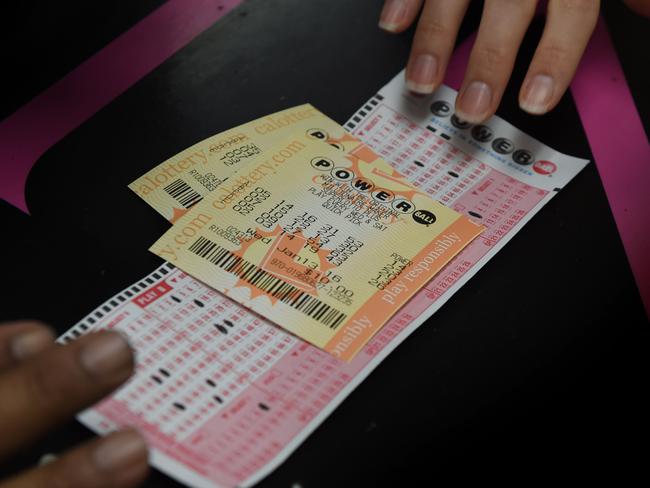 A customer picks up her California Powerball lottery tickets at the famous Bluebird Liquor store which is considered to be a lucky retailer of tickets, in Hawthorne, California on January 13, 2016. Record sales drove up the largest jackpot in US history to a whopping $1.5 billion as people dreaming of riches flocked across state lines and international borders to buy tickets. / AFP / MARK RALSTON