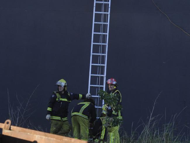 Firefighters place a ladder on a wall to try to get to the fire at Bankstown.