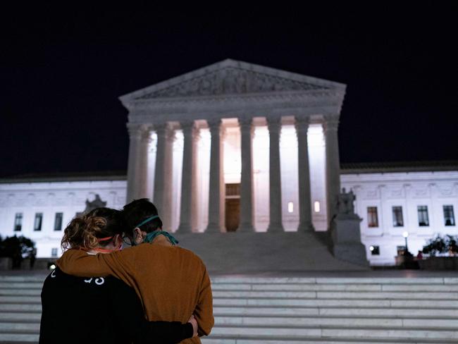 TOPSHOT - Two women embrace in front of the Supreme Court buidling paying their respects to Justice Ruth Bader Ginsburg after she died, in Washington, DC, on September 18, 2020. - Progressive icon and doyenne of the US Supreme Court, Ruth Bader Ginsburg, has died at the age of 87 after a battle with pancreatic cancer, the court announced on September 18, 2020. Ginsburg, affectionately known as the Notorious RBG, passed away "this evening surrounded by her family at her home in Washington, DC," the court said in a statement. (Photo by ALEX EDELMAN / AFP)