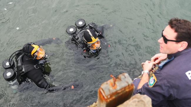 NSW Police divers briefing their dive boss during a search for evidence in Sydney Harbour. . Picture: John Grainger