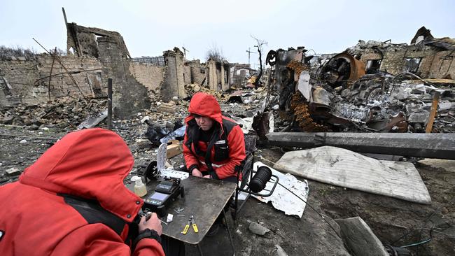 Repairmen restore local communication cables among the debris of destroyed armoured vehicles and buildings on a street in the town of Bucha, on the outskirts of the Ukrainian capital Kyiv. Picture: Genya Savilov / AFP