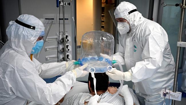 In this file photograph taken on December 30, 2021, medical staff members help a patient to wear a new non-invasive technology that can reduce the need of intubation at Covid-19 intensive care unit (ICU) at The Institute of Clinical Cardiology (ICC) in Rome. - The Covid-19 pandemic, which for over three years has killed millions of people, wreaked economic havoc and deepened inequalities, no longer constitutes a global health emergency, the WHO said on May 5, 2023. It is "with great hope that I declare Covid-19 over as a global health emergency", WHO chief Tedros Adhanom Ghebreyesus told reporters, estimating that the pandemic had killed "at least 20 million" people, nearly three times the official estimate. (Photo by Alberto PIZZOLI / AFP)