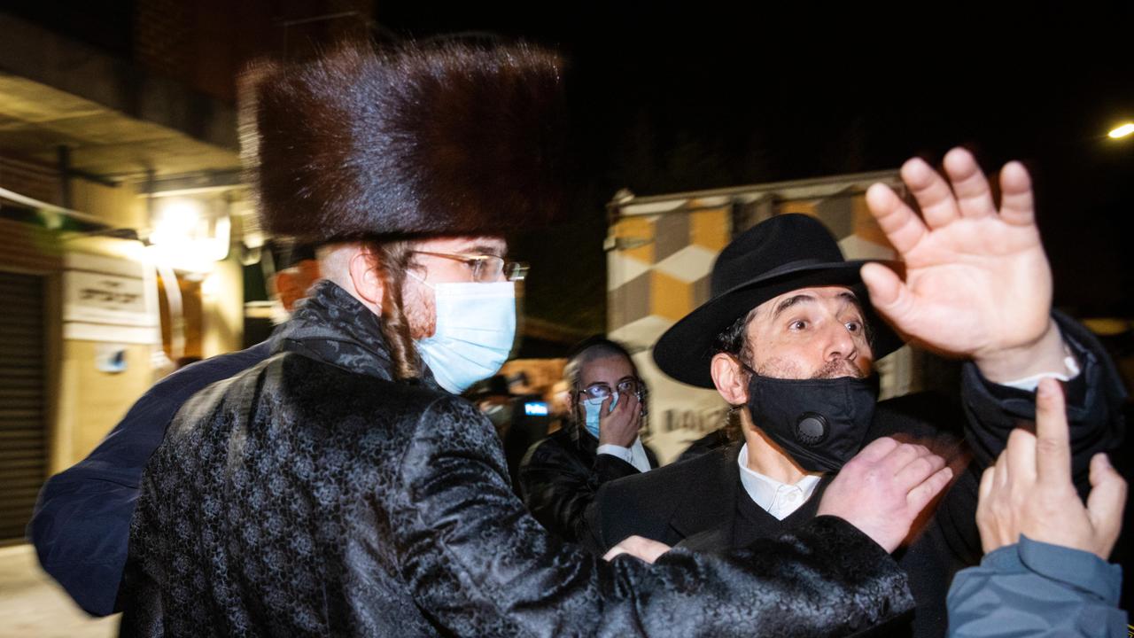 Members of the Caulfield Jewish community with the media as fellow community members are questioned by police as they leave an illegal gathering. News Corp is not suggesting these people are connected to the video footage in this story. Picture: Mark Stewart