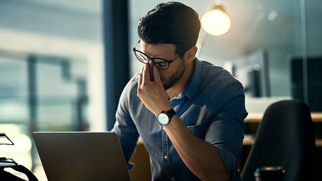 Shot of a young businessman experiencing stress during a late night at work