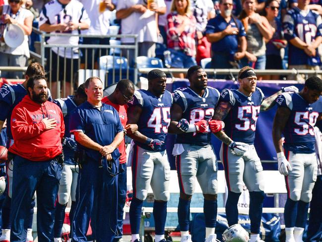 The New England Patriots lock arms as the US national anthem is played.