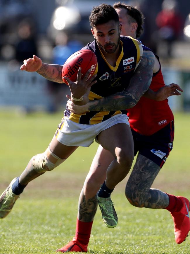 Matthew Knight of Rupertswood gathers the ball under pressure from Damon Cerini.