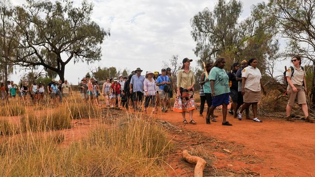 Local Anangu woman and Rangers take visitors on a interactive walk at the base of Uluru.