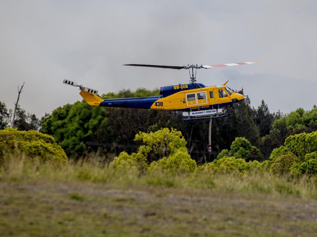 Smoke haze covers the Gold Coast Skyline from a grass fire at Carrara. A firefighting helicopter collects water from Judy Turners property in Carrara . Picture: Jerad Williams