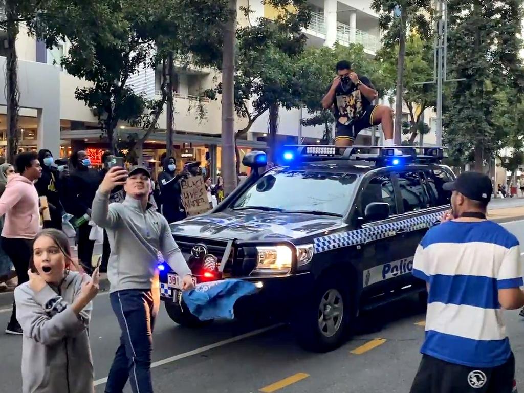 Screen grabs of a protester challenging police in Brisbane before jumping on top of the vehicle during Black Lives Matter protest rally in Brisbane.