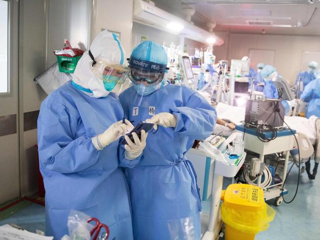 Medical staff treat check a mobile phone as they treat COVID-19 coronavirus patients at a hospital in Wuhan.