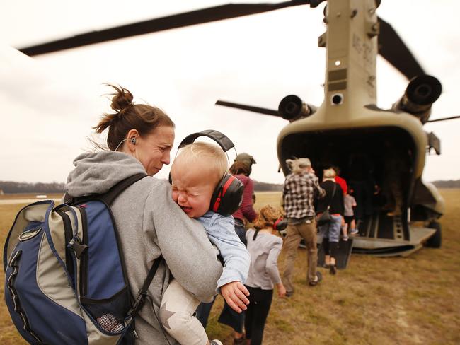 The last of the evacuees from Mallacoota are flown out in ADF Chinooks on Sunday. Picture: David Caird