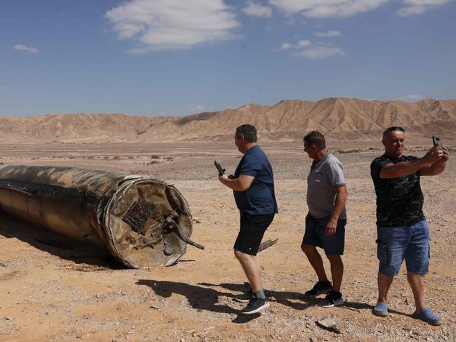 TOPSHOT - People take pictures near the remains of an Iranian missile in the Negev desert near Arad on October 2, 2024, in the aftermath of an Iranian missile attack on Israel the previous night. Israel vowed to make Iran "pay" for firing a barrage of missiles at its territory, with Tehran warning on October 2 it would launch an even bigger attack it is targeted. (Photo by Menahem KAHANA / AFP)