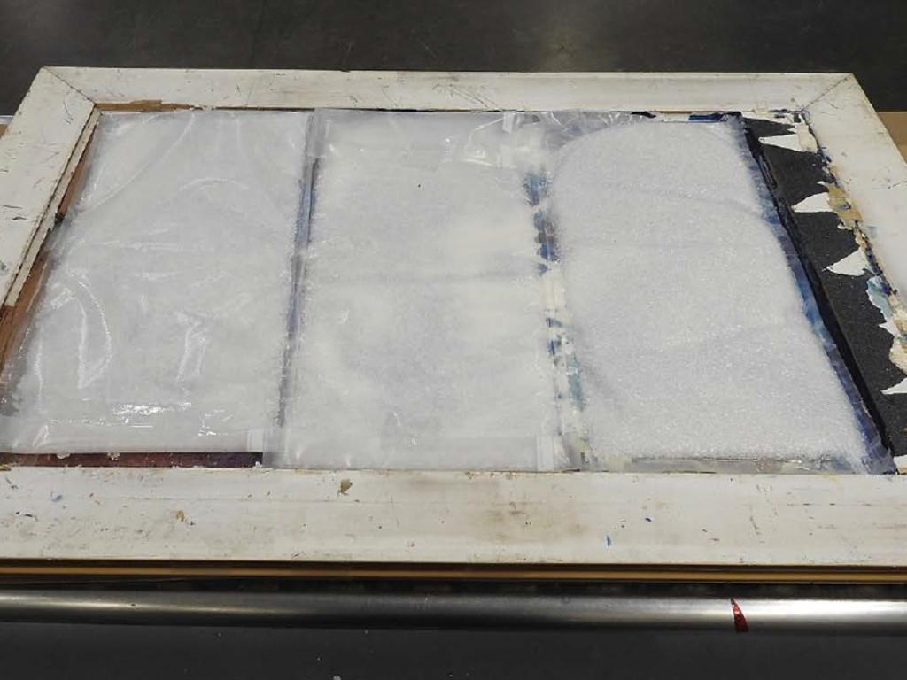 Police allegedly discovered three vacuum sealed bags containing a white crystalline substance, which tested positive for methamphetamine found stuck in the frame of a painting. Picture: AFP