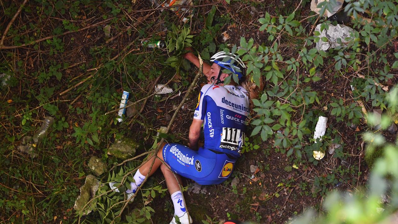 Remco Evenepoel lays on the ground after crashing over a bridge wall.