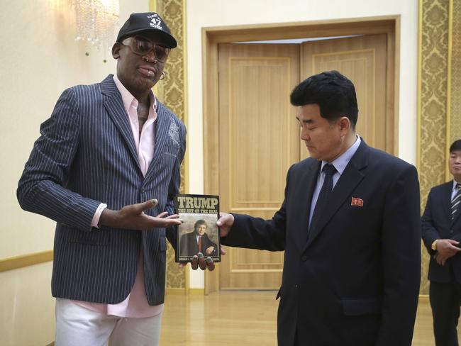 Dennis Rodman presents Donald Trump’s The Art of the Deal book to North Korean Sports Minister Kim Il Guk. Picture: AP Photo/Kim Kwang Hyon