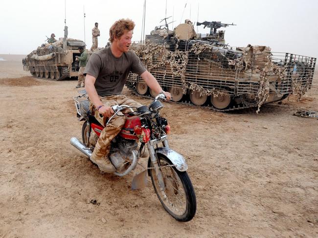 Prince Harry riding an abandoned motorcycle past his Spartan armoured vehicle, in the desert in Helmand province in Southern Afghanistan, February 2008. Picture: AFP