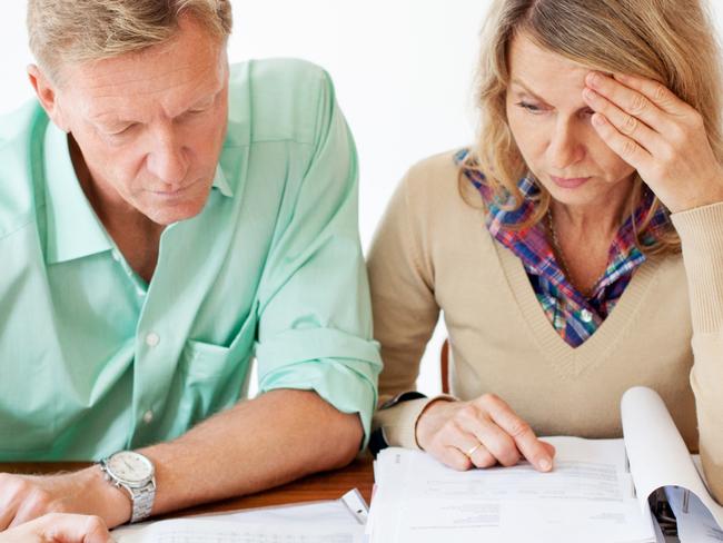 Middle aged couple sitting together at table and going through monthly expenses bills. They are experiencing stress. Picture: iStock.