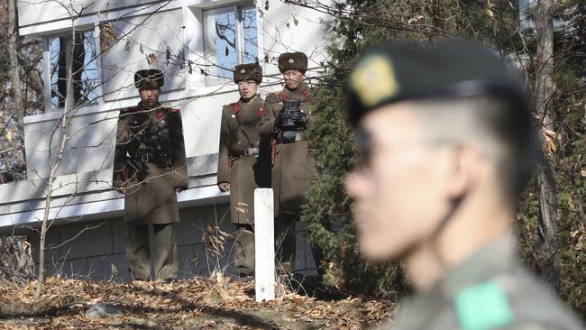 North Korean soldiers look at the South side as a South Korean stands guard near the spot where a North Korean soldier defected in November. Picture: AP/Lee Jin-man