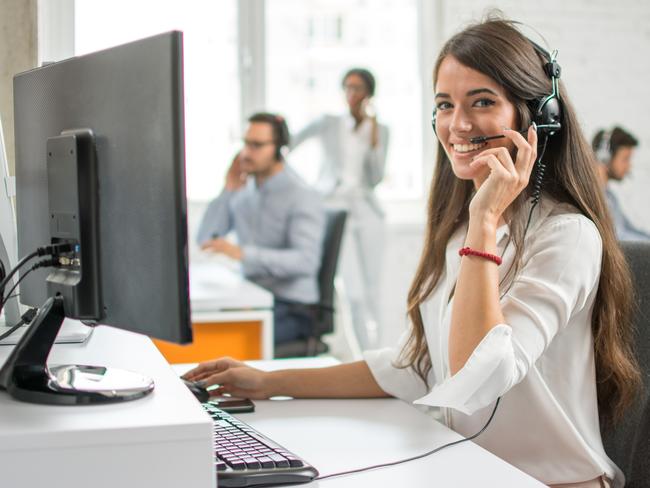 Young friendly operator woman agent with headsets working in a call centre.