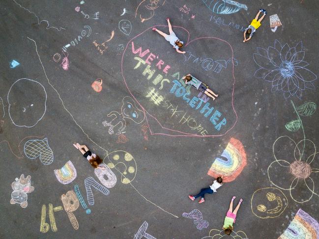 Kids practice social distancing while drawing and writing Corona themed chalk messages on the road in Eltham, Victoria. Picture: Jake Nowakowski