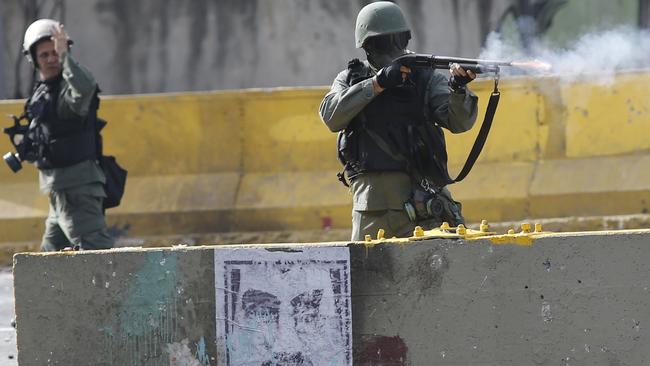 An officer fires at crowds during demonstrations in Caracas last month. Picture: AP