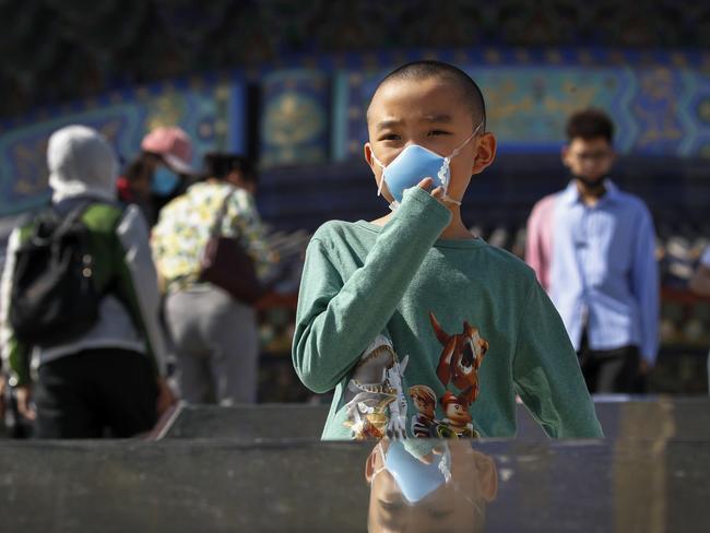 A child holds his protective face mask to help curb the spread of the new coronavirus in Beijing. Picture: AP