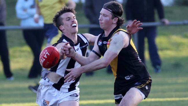 Lachlan Wilson gets a handball away under pressure from Josh Mills. Picture: George Salpigtidis