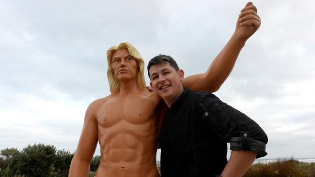 THUMBS UP: Joel Cousins, proprietor of Bombora on Goolwa Beach, with the cafe’s surfie mascot. Picture: Bernard Humphreys