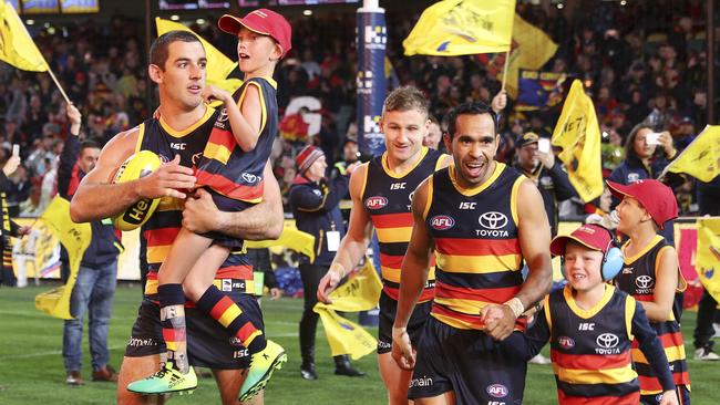 Taylor Walker and Eddie Betts run out with Crows mascots at the start of the game on Friday night. Picture: Sarah Reed