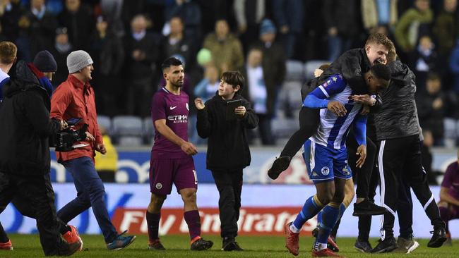 Manchester City's Argentinian striker Sergio Aguero (C) walks as supporters invade the pitch