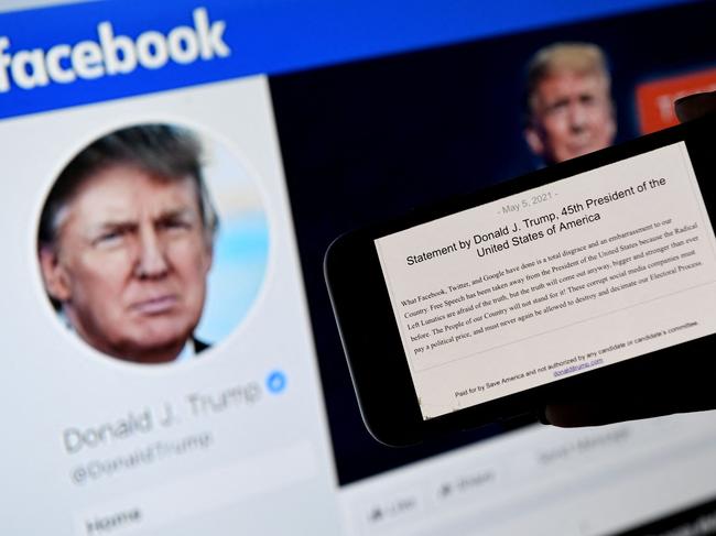 In this photo illustration, a phone screen displays the statement of former US President Donald Trump on his Facebook page background, on May 5, 2021, in Arlington, Virginia. - Donald Trump said May 5, 2021 it was a "total disgrace" for online giants to institute social media bans, after a Facebook board upheld the company's restriction against the former US president which he argued infringed on his free speech."What Facebook, Twitter, and Google have done is a total disgrace and an embarrassment to our country," Trump said in a statement. (Photo by Olivier DOULIERY / AFP)