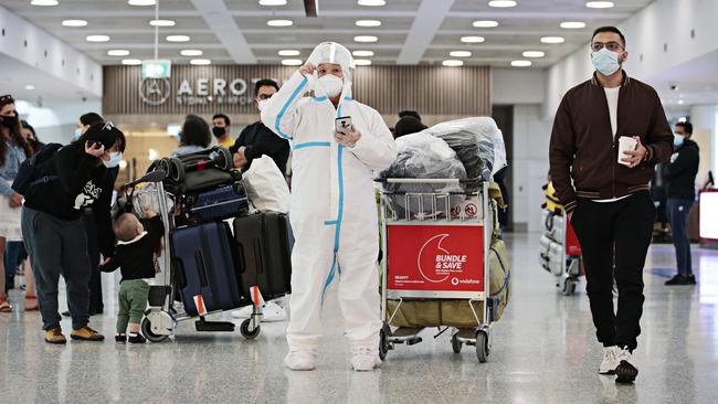 A passenger in protective gear arrives at Sydney International Airport on Sunday. Picture: Adam Yip