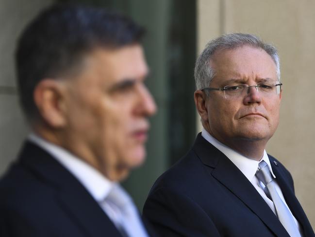 Australian Prime Minister Scott Morrison listens to Australia's Chief Medical Officer Brendan Murphy as he speaks to the media during a press conference at Parliament House in Canberra, Wednesday, March 18, 2020. (AAP Image/Lukas Coch) NO ARCHIVING