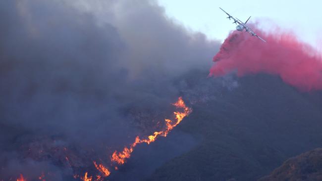 A firefighting aircraft drops the fire retardant Phos-Chek as the Palisades Fire burns amid a powerful windstorm. Picture: AFP