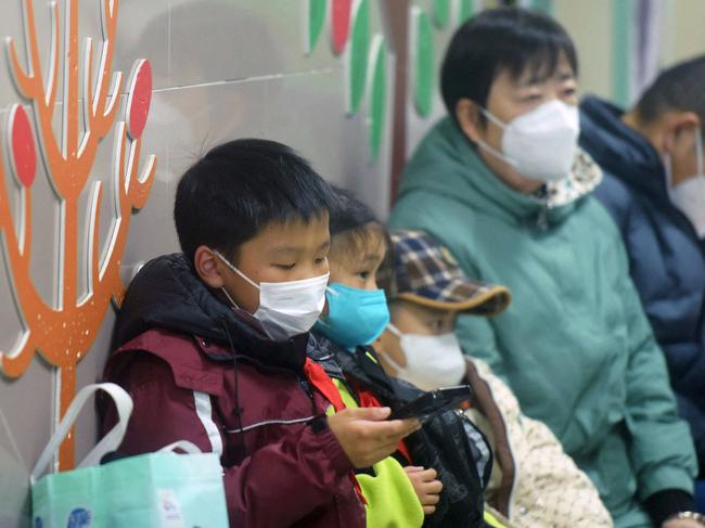 Masked children, accompanied by adults, wait to be seen by medical staff at the pediatric department of a hospital in Hangzhou, eastern China's Zhejiang province. Beijing has acknowledged a surge in cases of the flu-like human metapneumovirus (HMPV), especially among children, and attributed this to a seasonal spike. Picture: AFP