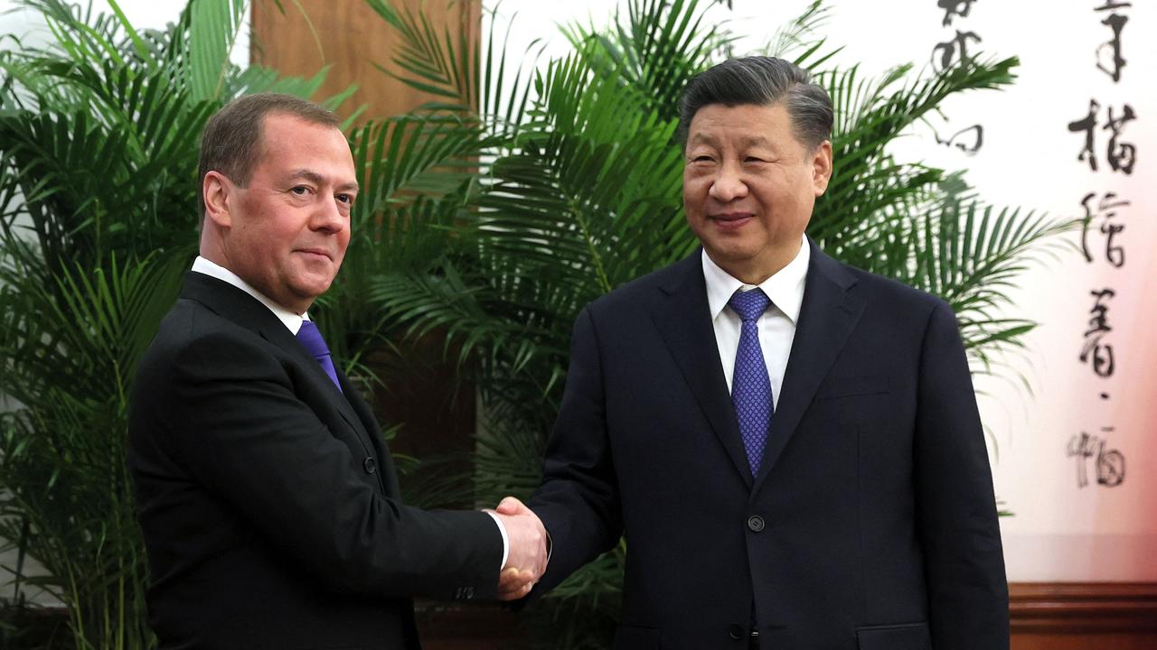 Deputy head of Russia's Security Council and chairman of the United Russia party, Dmitry Medvedev, shakes hands with Chinese President Xi Jinping. (Photo by Yekaterina SHTUKINA / Sputnik / AFP)