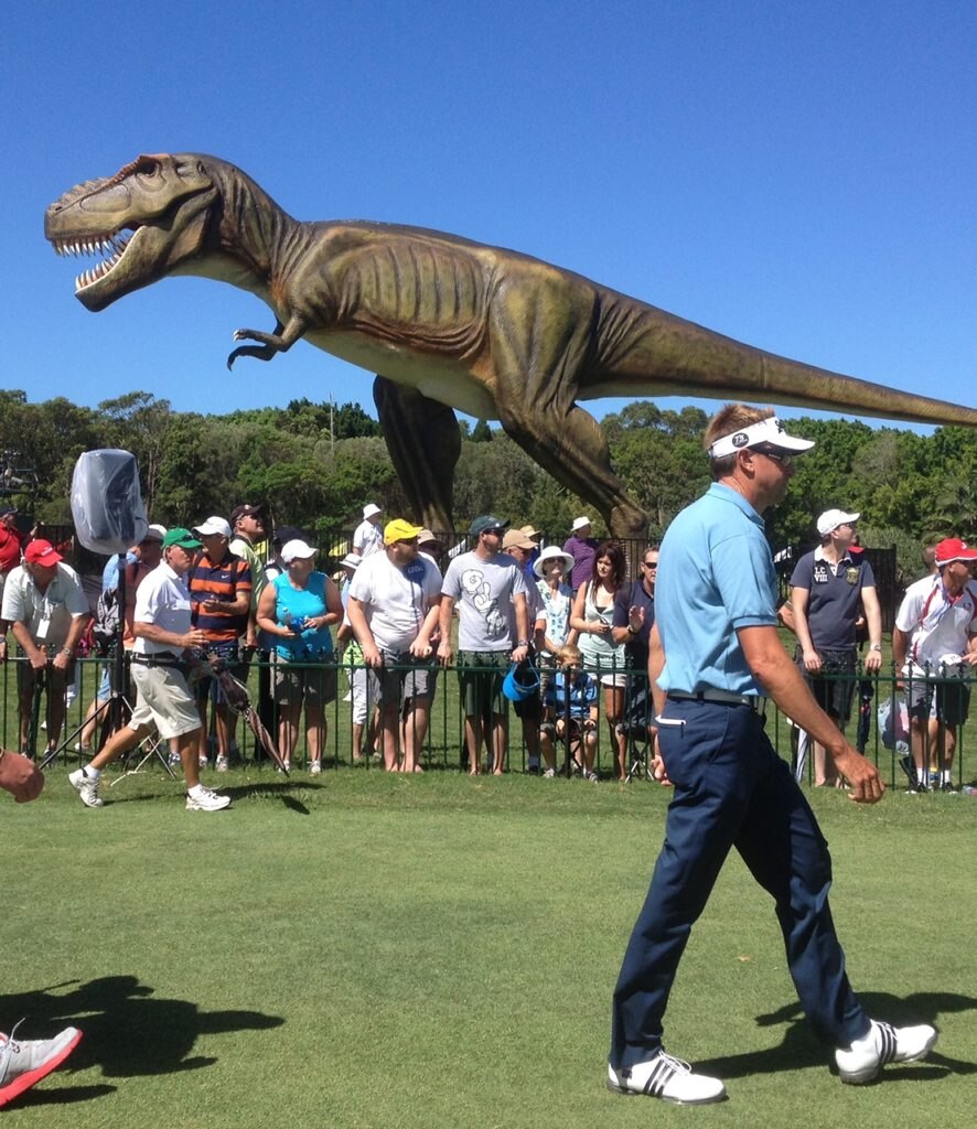 Robert Allenby walks past Clive Palmer's pet dinosaur 