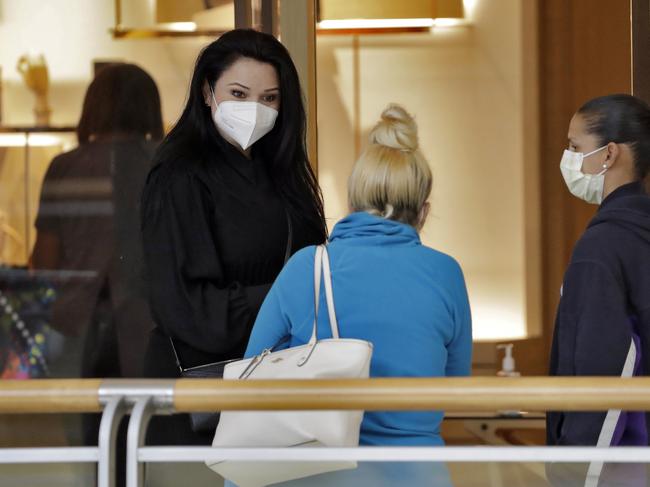 A worker at the Louis Vuitton store, left, wears a protective face mask as she talks to customers at a Florida store. Picture: AP