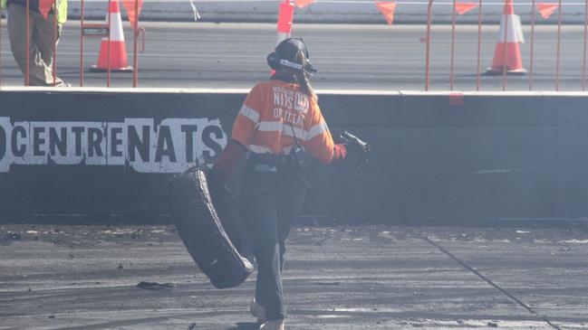 A Red CentreNATS official removes remnants from one of the many tyres popped on the burnout pad . Picture: Gera Kazakov